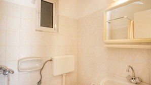 Een badkamer met toilet, wastafel en spiegel.