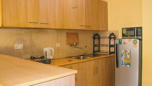 A compact kitchen with wooden cabinets, a stainless steel sink, a white refrigerator, and a microwave. - Elegant Stay near two rivers mall, Ruaka. (Ruaka)