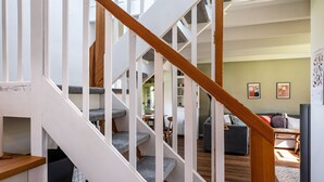 A staircase with wooden handrails and grey carpeted steps leading to a living area with a sofa, a coffee table, and artwork on the wall. - Charming Schlei Cottage Lorenz – Nature Retreat for Up to 4 Guests (Boren)