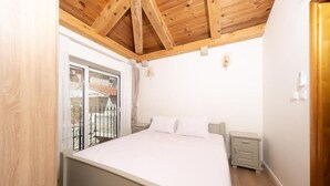 A bedroom with a wooden ceiling, a bed, a nightstand, and a sliding glass door leading to a balcony. - Castello degli Aranci Eco Resort (Krstac)