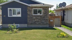 A single-story house with a stone facade and a dark blue exterior. - Cozy 2-Bedroom Suite | Private Access | Near Everything (Edmonton)
