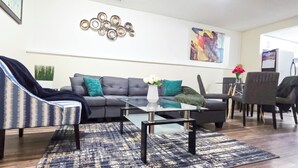 A modern living room with a grey sofa, striped armchair, and a glass coffee table. - Cozy 2-Bedroom Suite | Private Access | Near Everything (Edmonton)