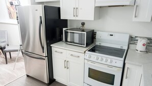A kitchen with white cabinets, a stainless steel refrigerator, a microwave, and a stove. - Cozy 2-Bedroom Suite | Private Access | Near Everything (Edmonton)