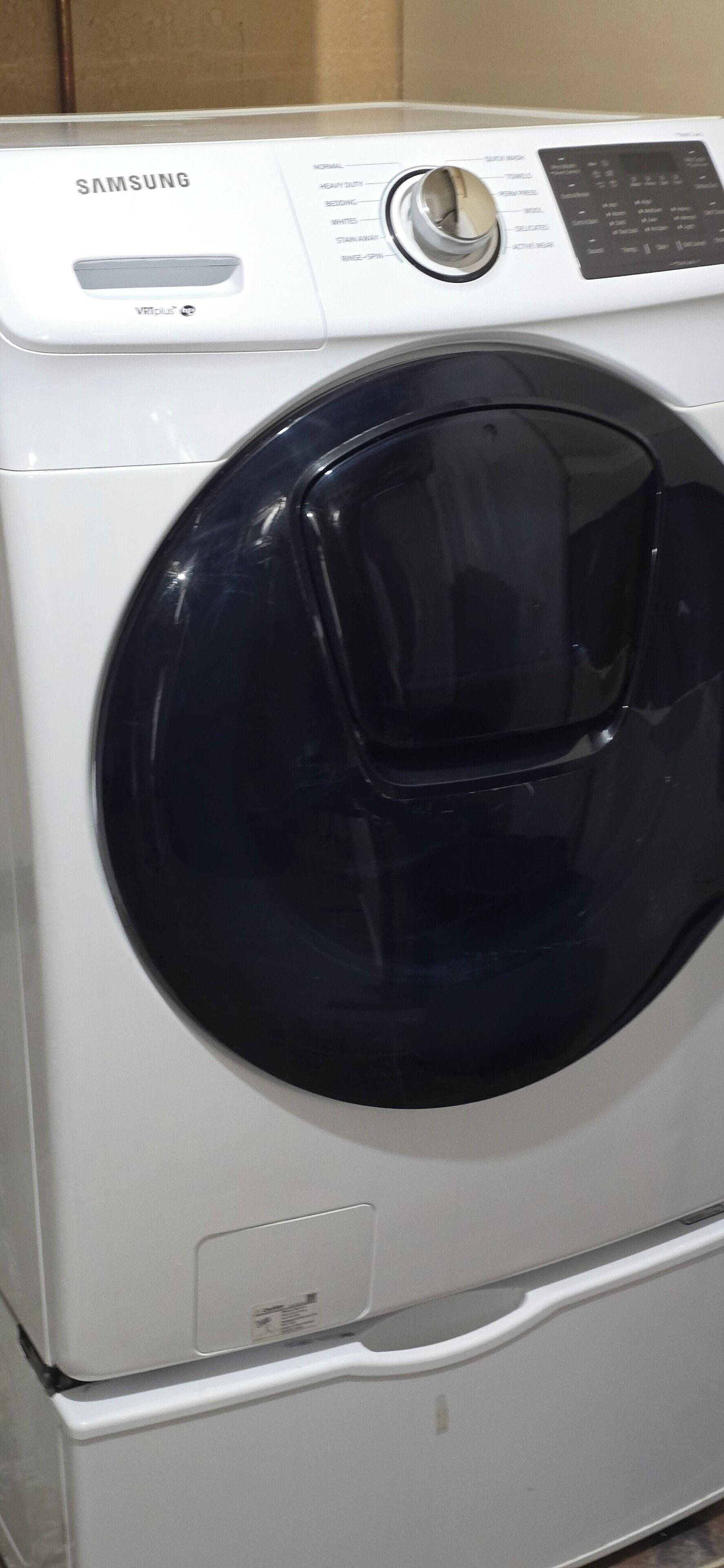 A Samsung washing machine with a control panel and a black door.