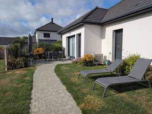 A modern house with a paved pathway leading to a patio area with two lounge chairs and a barbecue grill. - La Gloriette, 56 m2, 10 min from Berck, rated 3 stars (Verton)