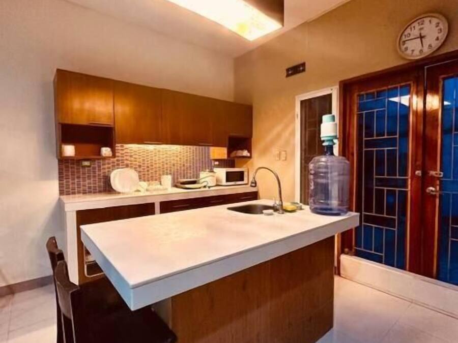 Une cuisine moderne dotée d’un îlot central, de meubles en bois, d’un four à micro-ondes et d’un grand distributeur d’eau.