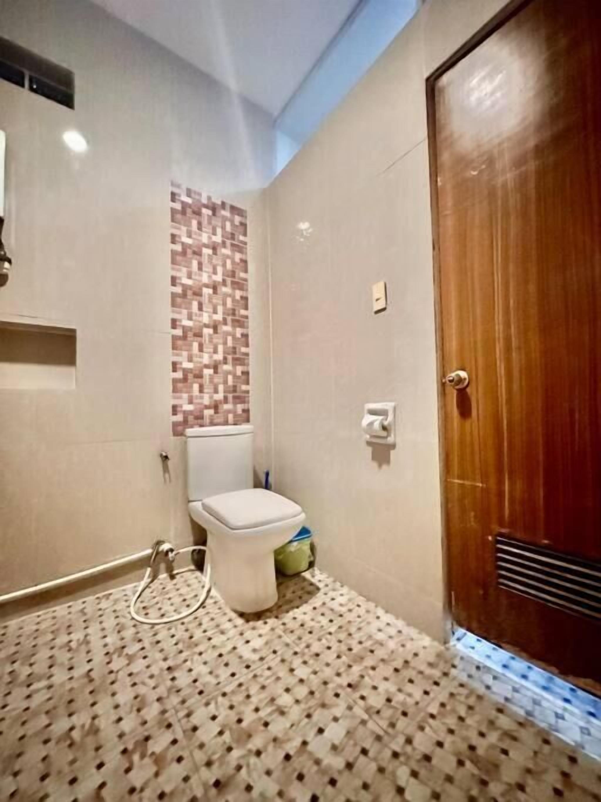 Un baño con inodoro, zona de ducha y puerta de madera.