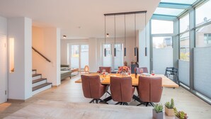 Ein moderner Essbereich mit einem Holztisch, braunen Stühlen und einer Glasdecke.
