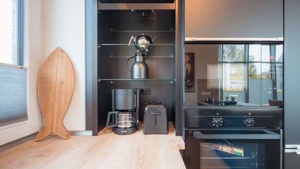 Eine moderne Küche mit integrierter Kaffeemaschine, Wasserkocher und Herd.