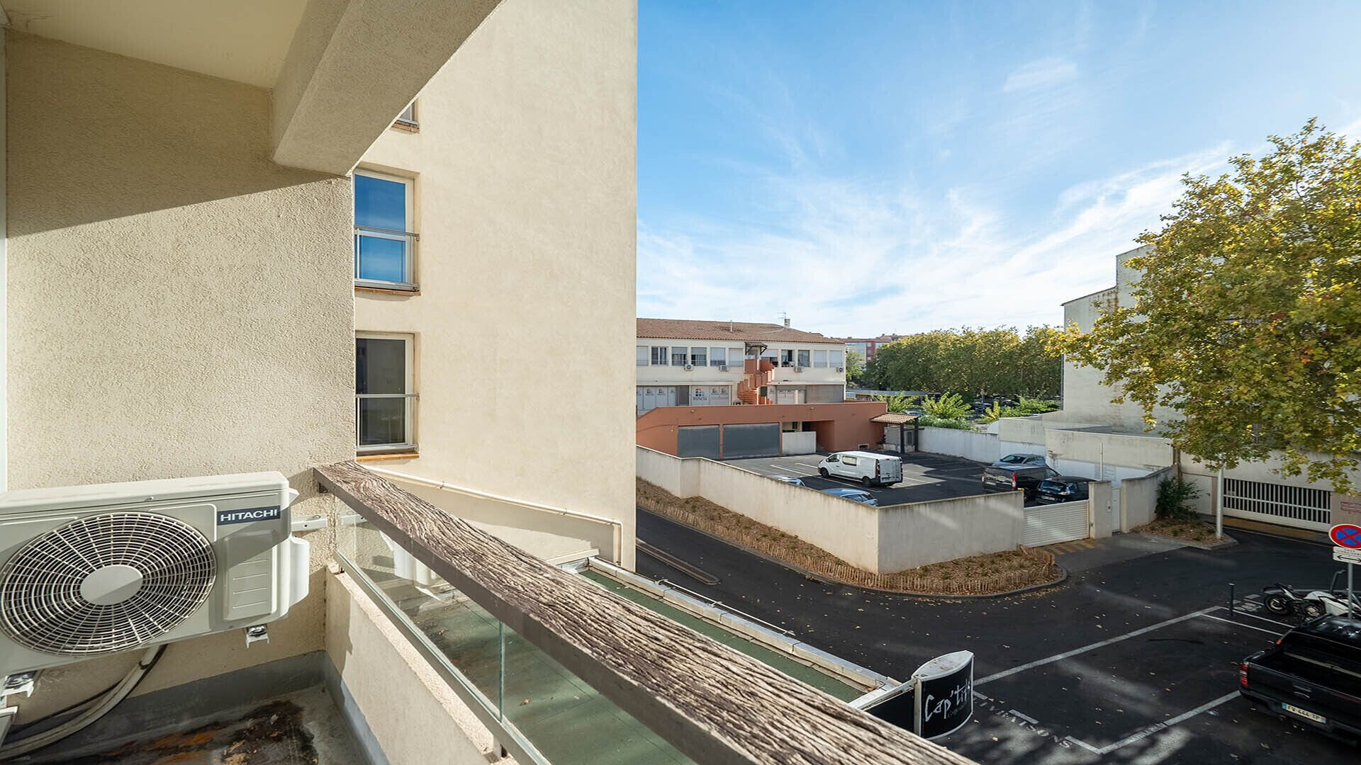 Ein Balkon mit Blick auf einen Parkplatz und Gebäude.