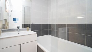 Ett modernt badrum med ett vitt handfat, en spegel och ett badkar.