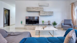Ein modernes Wohnzimmer mit Flachbildfernseher, Couchtisch und Sofa.