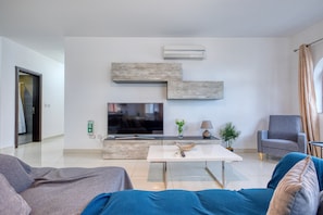 A modern living room with a flat-screen TV, a coffee table, and a sofa. - Bright, modern & spacious 3 bedroom flat MMIC1-1 (St Julian's)