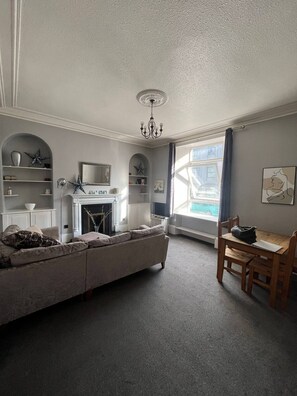 A living room with a fireplace, a sofa, a dining table, and a chandelier. - Charming City Apartment in the Heart of Aberdeen (Aberdeen)