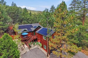 Eine Holzhütte mit Solaranlage, einer Holzterrasse und einer Treppe zum Eingang.