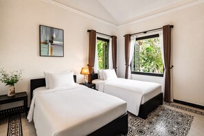 Habitación de hotel con dos camas, una mesita de noche, una lámpara, un cuadro y una ventana con cortinas.