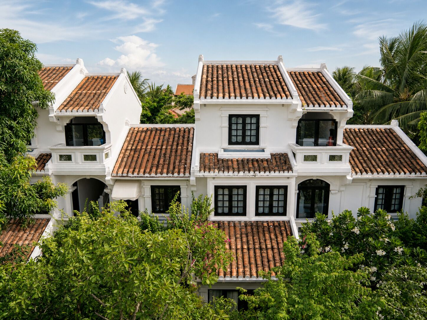 Un edificio de estilo colonial blanco con varios techos de tejas y ventanas amplias.