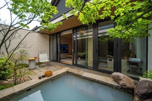 Una casa moderna con piscina, un patio con mesa y sillas, y un amplio ventanal corredero que da a un espacio interior.