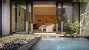 A modern spa area with a hot tub, a seating area with a table and chairs, and a glass door entrance. - Beijing Wanli Yipiao Courtyard Hot Spring Resort (Beijing)