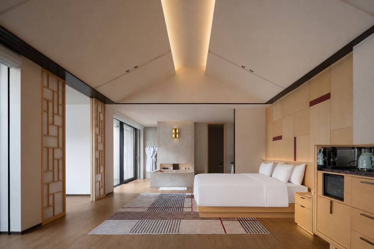 Une chambre d’hôtel moderne dotée d’un grand lit, d’une kitchenette et offrant une vue sur la ville.