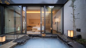 A modern spa with a hot spring, glass doors leading to a room with a bed and a bathroom, and ambient lighting. - Beijing Wanli Yipiao Courtyard Hot Spring Resort (Beijing)