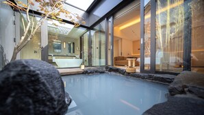 A modern spa with a glass-enclosed pool, a sitting area with a sofa, and a visible bathroom with a bathtub. - Beijing Wanli Yipiao Courtyard Hot Spring Resort (Beijing)