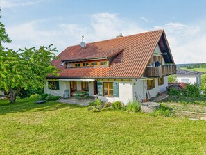 A two-story house with a sloped roof, a balcony, and a garden. - Holiday Home “With Sun Terrace” with Balcony and Wi-Fi (Ostrach)