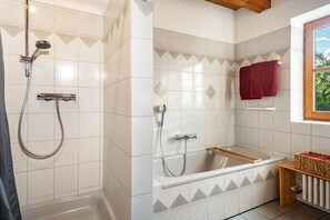 Une salle de bain avec une douche, une baignoire et une fenêtre.