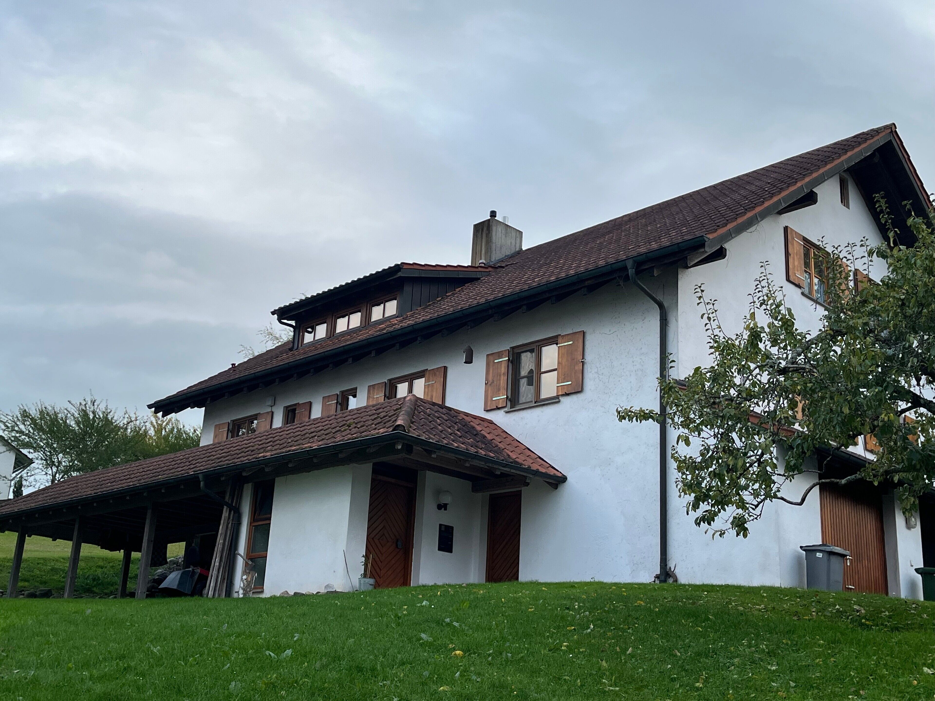 Ein zweigeschossiges Haus mit geneigtem Dach, Holzhörnern und einer Veranda.