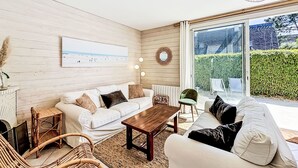 En moderne stue med en hvid sofa, et træbord og fletstole.