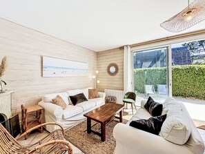 A modern living room with a white sofa, a wooden coffee table, and wicker chairs. - Ty Bottez by Interhome (Carnac)