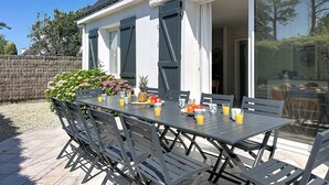 En udendørs patio med spisebord og stole, omgivet af en murstensmur i baggrunden.