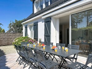 An outdoor patio with a table set for two, surrounded by chairs, and a stone wall in the background. - Ty Bottez by Interhome (Carnac)