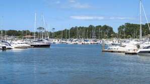 Ein Yachthafen mit zahlreichen Booten, ruhigem Wasser und bewaldeter Landschaft im Hintergrund.