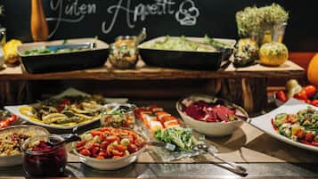 Ein reichhaltiges Buffet mit verschiedenen Speisen und einem Kreidetafel-Schild mit der Aufschrift 'Guten Appetit'.