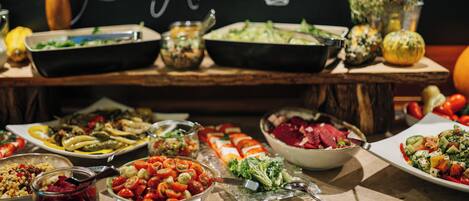 A buffet table with various dishes and a chalkboard sign reading "Guten Appetit".