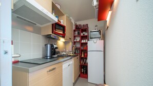 Egy praktikus, kis méretű konyha, amelyben mikrohullámú sütő, pirító és egy kisebb hűtőszekrény található.