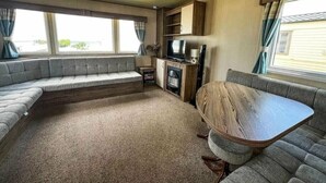 Ein kompaktes Wohnmobil-Interieur mit einer Sitzecke, einem Holztisch, einem Fernseher und einem Kamin.