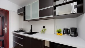 Una cucina moderna con mobili scuri, un piano di lavoro bianco, un forno a microonde, una macchina da caffè e un fornello a gas.