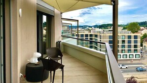 Ein Balkon mit Blick auf die Stadt, ein Stuhl, ein kleiner Tisch und ein Blumentopf.