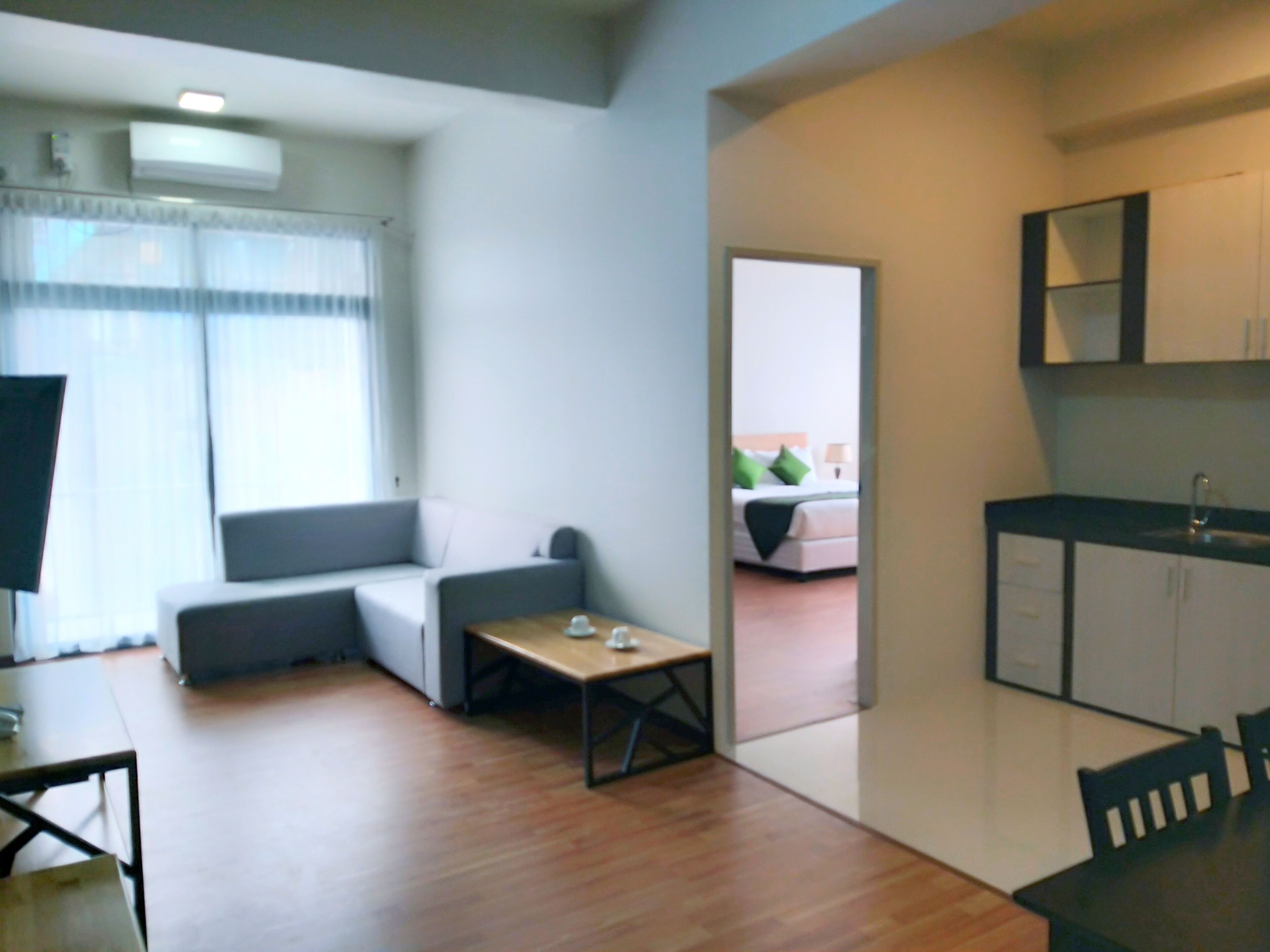 Una sala moderna con un sofá, una mesita y una zona de cocina con armarios y un lavamanos.