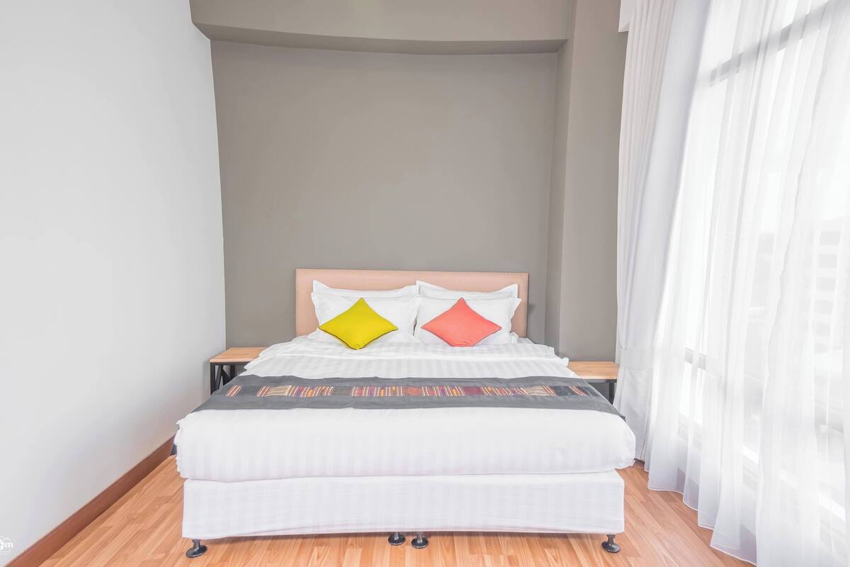 Una cama bien hecha con un cabecero, dos almohadas y una mesita de noche.