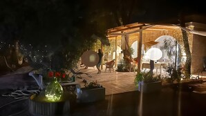 Ein Außenbereich mit Patio, überdachter Sitzgruppe, Kübelpflanzen und einer Steinmauer.