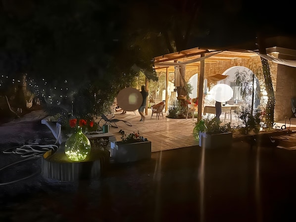 An outdoor patio area with a covered seating area, potted plants, and a stone wall.