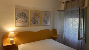Ein Schlafzimmer mit einem Bett, einem Nachttisch mit Lampe und drei gerahmten Wandbildern.