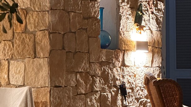Eine Steinsäule mit einer Lampe, einem Korbstuhl und einem Handtuch an einem Wäscheständer.