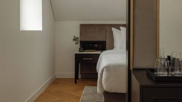 Ein Schlafzimmer mit schrägverdeckter Decke, einem Bett, einem Nachttisch, einer Kommode und einem großen Spiegel.