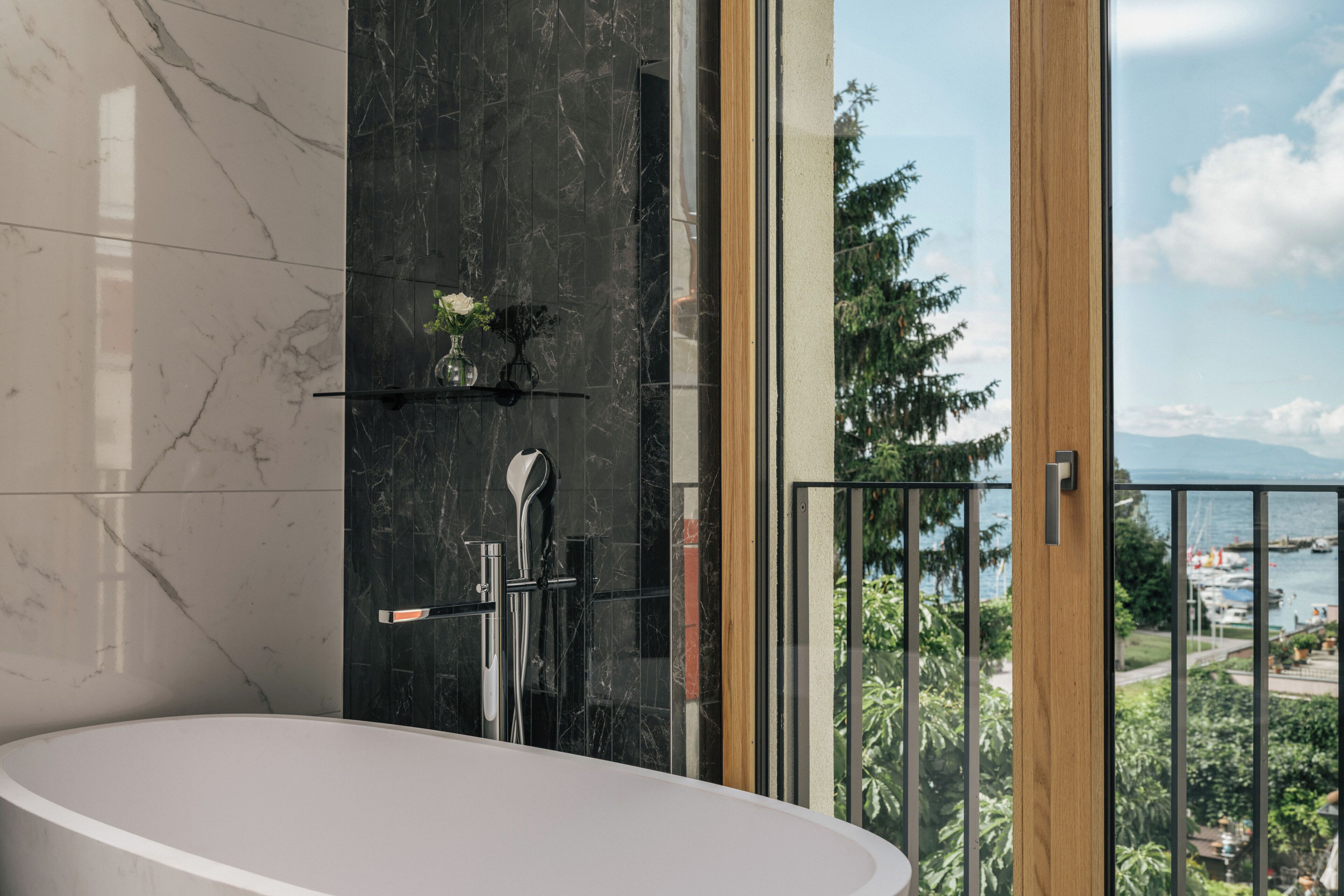 A modern bathroom with a bathtub, a shower, and a view of the outdoors.