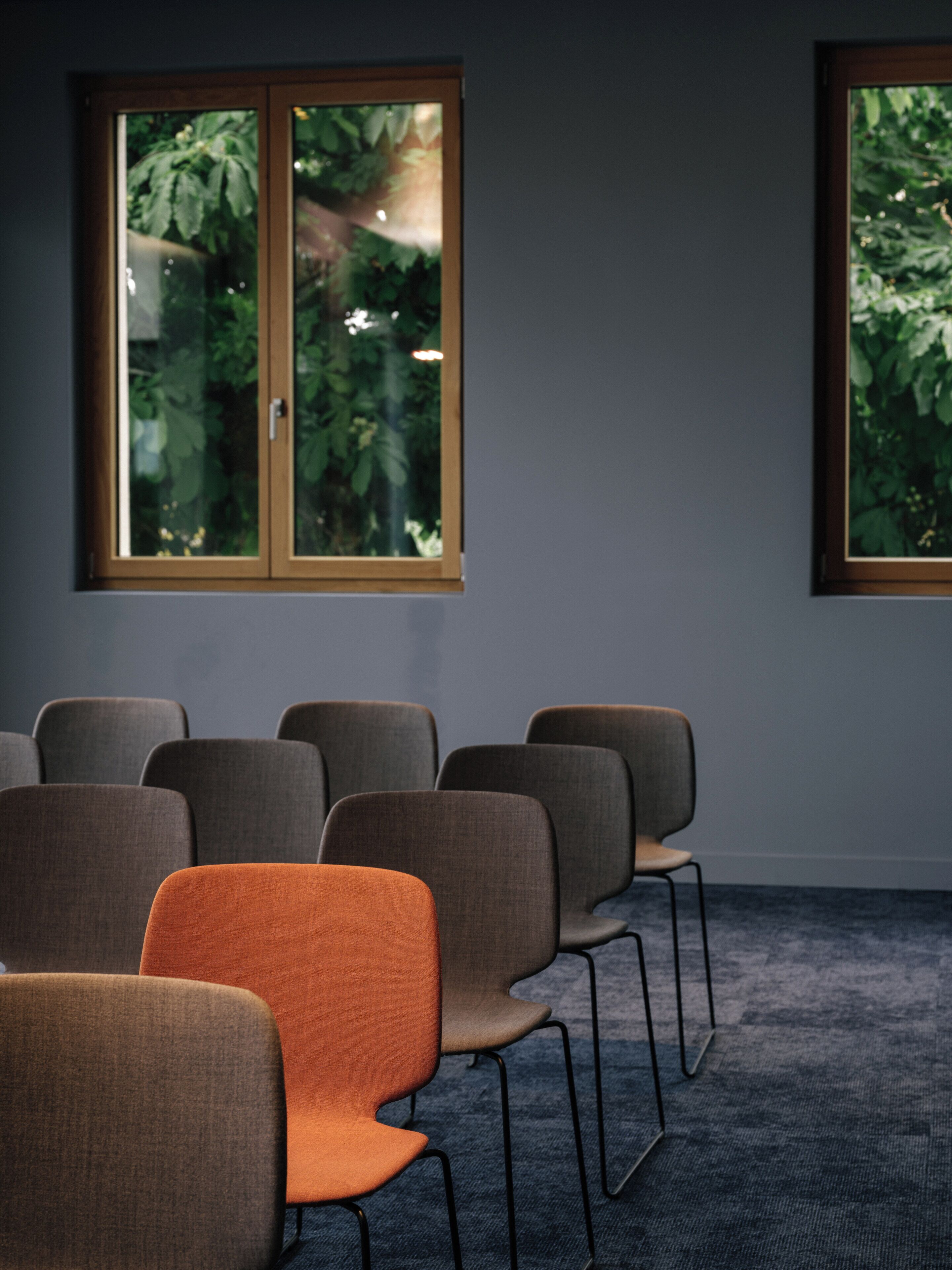 Une pièce avec une rangée de chaises, une fenêtre et une porte.