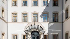 Fachada de hotel simétrica con un arco central y varias ventanas.
